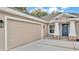 Close-up of a home featuring a wide two-car garage, a charming front door, and stylish exterior lighting at 803 Allison Place, Bartow, FL 33830