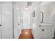 Hallway featuring hardwood floors, white doors, lighting fixture, and a glimpse of the bathroom at 112 Hiawatha Trl, Lakeland, FL 33803