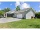 Exterior view of home featuring a two-car garage, screened porch, well-manicured lawn, and private driveway at 117 Palmola St, Lakeland, FL 33803