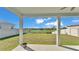 Backyard view from covered patio overlooking grassy lawn and tranquil pond in the distance at 1280 Denali Dr, Winter Haven, FL 33880