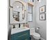 Stylish powder room boasts a teal vanity, gold accents, and a unique, modern mirror design at 13137 Lake Butler Blvd, Windermere, FL 34786