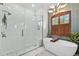 Modern bathroom featuring a glass enclosed shower and standalone tub near window with wooden shutters at 13137 Lake Butler Blvd, Windermere, FL 34786