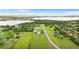 Picturesque aerial view of a well-maintained property with lush greenery, mature trees, and a beautiful lake in the background at 150 Berkley Knights Dr, Auburndale, FL 33823