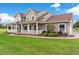 Inviting two-story home featuring a charming wrap-around porch and landscaped front yard at 150 Berkley Knights Dr, Auburndale, FL 33823
