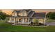 Beautifully lit home at dusk featuring a wrap-around porch and lush green lawn at 150 Berkley Knights Dr, Auburndale, FL 33823
