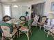 Bright sun room featuring a glass table with wicker chairs and green carpeting at 1610 Reynolds Rd # 80, Lakeland, FL 33801