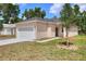 Cozy single-story home with a front lawn featuring a young tree and driveway leading to the garage at 1890 Martin Luther King, Jr. E Blvd, Bartow, FL 33830