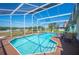 Backyard view of a screened pool and spa with patio furniture and green space beyond at 217 Dillon Way, Davenport, FL 33897
