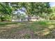 The backyard features a lush green lawn and mature trees providing ample shade at 2400 Avenue D Sw, Winter Haven, FL 33880