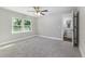 This bedroom features gray carpet, a ceiling fan, and a view of a leafy tree from the window at 2400 Avenue D Sw, Winter Haven, FL 33880