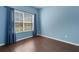 Blue bedroom with window and curtains, hardwood floors, and natural light at 4089 Shade Tree Ln, Lakeland, FL 33812