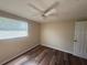 Neutral bedroom showcasing wood flooring, a ceiling fan, a window, and a closet door at 4830 Melody Ln, Lakeland, FL 33805