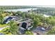 Home with a pool, three-car garage, circular driveway, and lake view surrounded by lush greenery at 5087 Cliffside Drive, Lakeland, FL 33813
