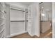 Walk-in closet featuring custom shelving and hanging racks adjacent to modern bathroom at 5087 Cliffside Drive, Lakeland, FL 33813