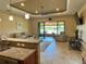 Open-concept living room with tan sofas and chairs, and sliding glass doors to lanai with lake view at 564 Meandering Way, Polk City, FL 33868