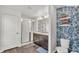 Modern bathroom with a double vanity, walk-in shower, and stylish wallpaper at 613 Sarner Pass Way, Winter Haven, FL 33881