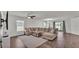 Spacious living room featuring a large sectional sofa, ceiling fan, and sliding glass doors to the backyard at 613 Sarner Pass Way, Winter Haven, FL 33881
