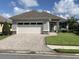 Well-maintained single-story home with a large garage, brick driveway, and manicured front lawn at 7779 Lake James Blvd, Lakeland, FL 33810