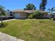 Charming ranch home with an attached garage, lush lawn, palms, and an RV parked in the driveway at 7818 Lewis Rd, Lakeland, FL 33810