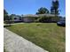 Charming ranch home with an attached garage, lush lawn, palms, an RV, and a car parked in the driveway at 7818 Lewis Rd, Lakeland, FL 33810
