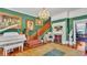 This living room features a white piano, green walls, hardwood floors, a fireplace, and staircase at 822 W Patterson St, Lakeland, FL 33803