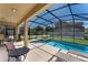 Backyard view of a screened in pool with a nearby lounge area, chairs, and table at 8931 Sugar Palm Rd, Kissimmee, FL 34747