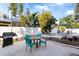 Outdoor patio with a dining table, lounge chairs, barbecue grill, and lush tropical landscaping at 934 Lake Elbert Se Dr, Winter Haven, FL 33880
