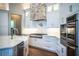 Beautiful kitchen featuring white cabinets, quartz counters, stainless appliances, and a stone vent hood at 942 Hanover Way, Lakeland, FL 33813