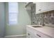 The laundry room boasts an elegant tile backsplash, ample natural light, and modern sink at 942 Hanover Way, Lakeland, FL 33813