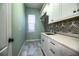 A spacious laundry room features modern tile backsplash, white cabinetry, and a sink at 942 Hanover Way, Lakeland, FL 33813