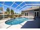 Screened-in pool area with mature landscaping, a built-in spa, and beautiful blue water at 942 Hanover Way, Lakeland, FL 33813
