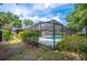 Back exterior view of the home featuring a screened in pool and green shrubbery at 1104 Kells Ct, Lakeland, FL 33813