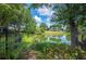 Picturesque lake view with lush landscaping, mature trees, and a glimpse of the home in the background at 1104 Kells Ct, Lakeland, FL 33813