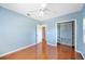 Light blue bedroom features wood floors, a ceiling fan, and a closet with built in shelving at 1104 Kells Ct, Lakeland, FL 33813