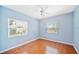 Bright blue bedroom featuring wood floors, two windows, and a ceiling fan at 1104 Kells Ct, Lakeland, FL 33813