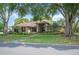 Charming single-story home featuring mature trees, a well-manicured lawn, and a welcoming entrance at 1104 Kells Ct, Lakeland, FL 33813