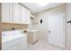 Functional laundry room with washer, sink, cabinets, and door to the rest of the house at 1104 Kells Ct, Lakeland, FL 33813