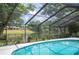 Inviting screened pool area with a sparkling pool and scenic views of the backyard pond and lush greenery at 1104 Kells Ct, Lakeland, FL 33813