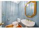Charming half bath featuring a pedestal sink, decorative mirror, and elegant fixtures at 1104 Kells Ct, Lakeland, FL 33813
