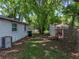 Wide view of the backyard with mature trees, shed, and white vinyl siding at 1720 Kendrick Ln, Lakeland, FL 33805
