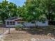 Front of the house with mature trees, a fence, and updated siding at 1720 Kendrick Ln, Lakeland, FL 33805