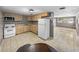 Efficient kitchen with wood cabinets, white appliances, tile floors, and easy access to adjacent living room at 1720 Kendrick Ln, Lakeland, FL 33805