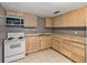 Kitchen featuring wood cabinets, laminate countertops, and standard appliances on tile floors at 1720 Kendrick Ln, Lakeland, FL 33805