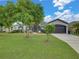 Well manicured lawn with mature tree highlights this home's charming exterior and convenient two-car garage at 2033 Normandy Heights Dr, Winter Haven, FL 33880