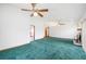 Open-concept living room with green carpet, ceiling fans, and hallway access at 3226 Cherry Hill S Cir, Lakeland, FL 33810