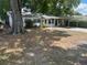 Simple one-story home with carport and mature trees in the front yard, showing some wear at 411 Keat Ave, Auburndale, FL 33823