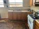 Kitchen with a sink, stove, and damaged flooring and cabinets at 445 Choctaw Ave, Lakeland, FL 33815
