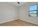 Bright, minimalist bedroom featuring hardwood floors, neutral walls, and a window with a view of the neighborhood at 5374 Clubhouse Hills Ln, Lakeland, FL 33812