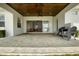 Covered patio features stone pavers, ceiling fan, and outdoor grill, with a view inside to the kitchen at 6627 Ridgemont Rd, Lakeland, FL 33813