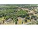 Aerial view of a property featuring a home, outbuildings, and a surrounding landscape filled with lush trees at 7011 Tall Pine Rd, Polk City, FL 33868